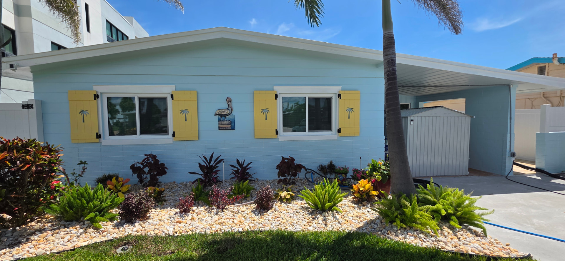 Coastal cottage painted light blue with yellow palm-tree shutters and white trim